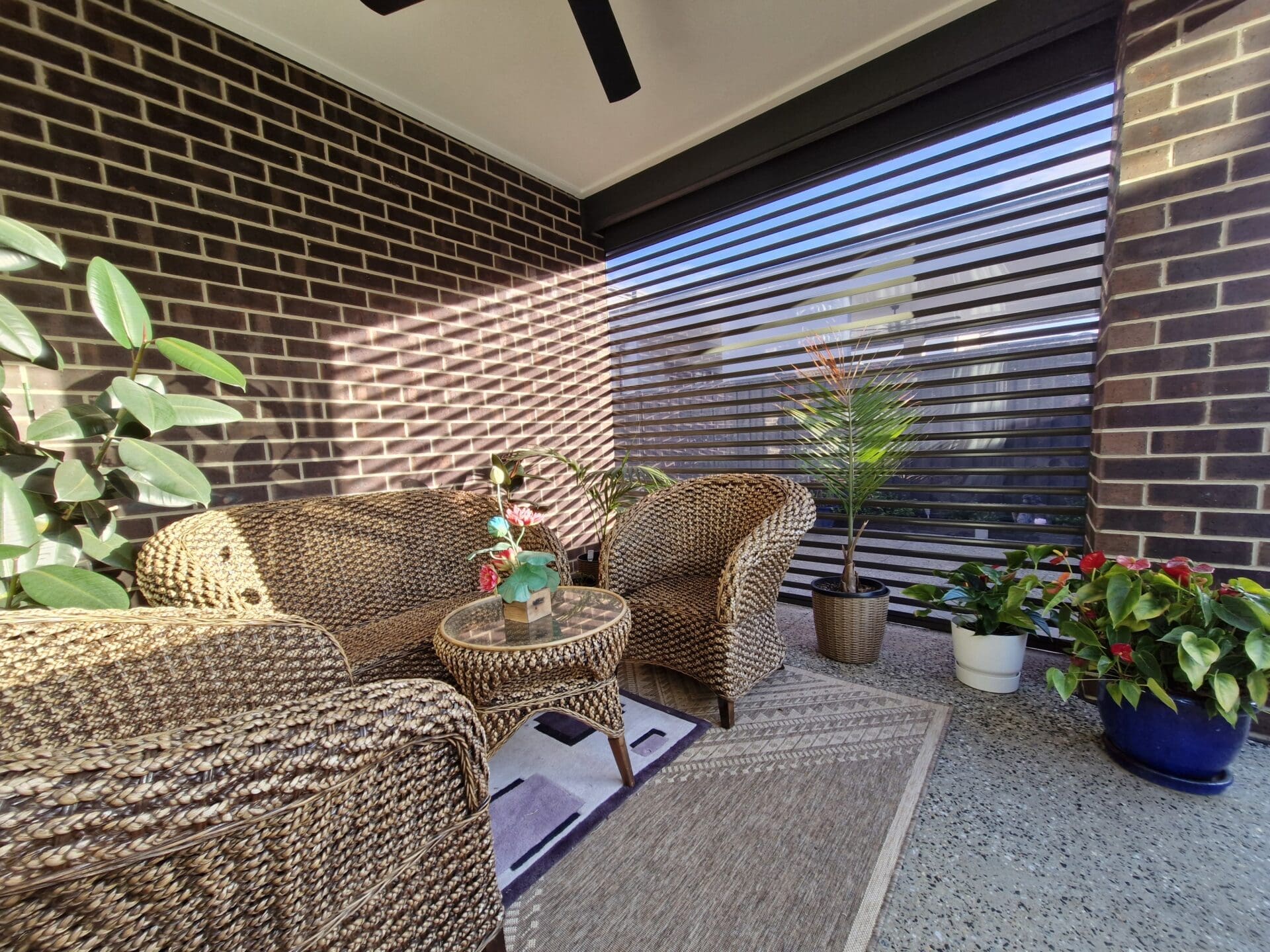 Australian roller shutters a patio with a brick wall and a chair and a table